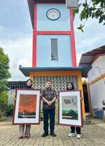 　金守世士夫さんの版画作品２枚をインドネシアの南タンゲラン市にある「ひかり小学校」に届けた「インドネシア教育振興会」代表理事の窪木靖信さん（中央）＝２０２５年１月（同会提供）