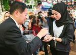 　４日、マレーシアの首都クアラルンプールで、ホタテを買い物客に振る舞う宮下農相（左）（共同）