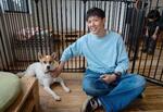 　キドックスのカフェで保護犬のふうちゃんと遊ぶ岡本達也。居場所が他の犬たちと柵で仕切られている＝２０２４年５月、茨城県つくば市