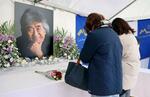 　小澤征爾さんの笑顔の写真が飾られた献花台を訪れ、別れを惜しむ人たち＝１０日午後、長野県松本市