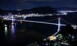 　開通５０周年を前にライトアップされた、北九州市（奥）と山口県下関市を結ぶ関門橋＝１２日夜