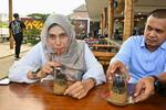 　逆さコーヒーを楽しむリリン・フェグリナさん（左）ら＝２０２３年１２月、インドネシア・バンダアチェ（共同）