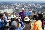 首都圏から訪れたツアー客を米子城跡でガイドする川越理事長＝２０１９年４月、鳥取県米子市久米町