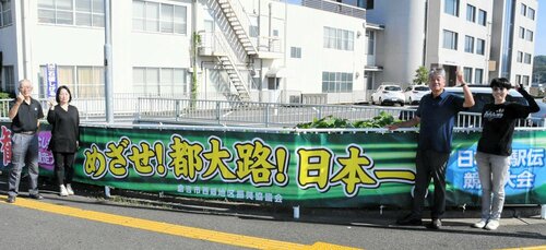 選手を応援する横断幕と西郷地区まちづくり協議会のメンバーら＝倉吉市八屋