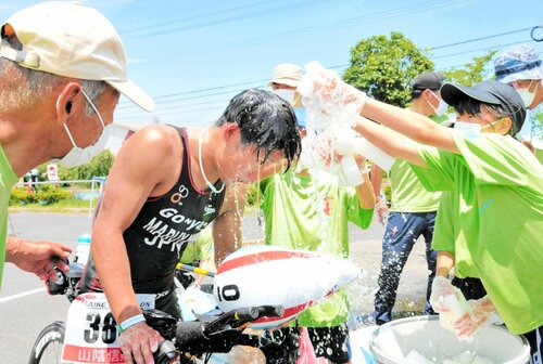 エイドステーションで選手に水をかけるボランティア＝２０２２年７月１７日、大山町の中山農業者トレーニングセンター