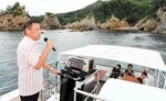 浦富海岸の島を巡りながら、歌声を響かせるモニター客（左）＝１４日、岩美町田後付近の浦富海岸