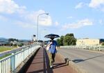 　厳しい暑さの中、日傘を差して歩く男性＝５日午後、福島県伊達市