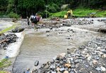 台風７号災害で土砂が流入し、山から流れ落ちる水で川のようになった国道４８２号＝２０２３年８月１７日、鳥取市佐治町余戸