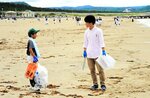 交流のひととき　イベントには鳥取環境大生も参加した。「たくさん拾ったね」。児童と交流しながらごみ拾い