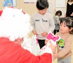 【ありがとう】笑顔でサンタクロース（手前左）からプレゼントを受け取る子どもたち