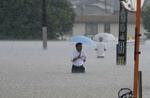 　大雨の影響で冠水した道路を歩く人＝７月、福岡県久留米市