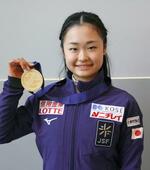 　フィギュアスケートの世界ジュニア選手権から帰国し、金メダル手に笑顔の島田麻央＝４日、関西空港