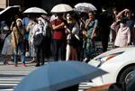 　気温が上がり、東京・銀座で日傘を差して信号を待つ人たち＝１４日午後
