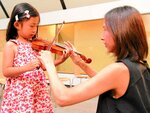 岡野さん（右）の指導でバイオリンに挑戦する子ども＝１３日、三朝町三朝の三朝バイオリン美術館