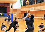 武田コーチ（中央）からボールを高く遠くに飛ばすための体の正しい使い方を学ぶ児童生徒たち＝１日、香美町村岡区の射添体育館