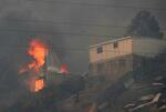 　３日、森林火災が起きたチリ中部バルパライソ郊外で燃える家屋（ロイター＝共同）