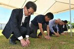 芝の苗を植えてグラウンドの芝生化の完了を祝う関係者ら＝２８日、境港市誠道町