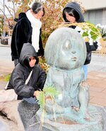 鬼太郎のブロンズ像にしめ縄を飾り付ける高校生ボランティア＝２６日、鳥取県境港市大正町