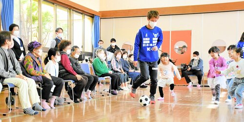 サッカーのミニゲームで子どもと対戦する田村選手（中央）と、それを見守る入居者ら