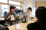　カフェ「Ａｓｔｒａｌ　Ｒａｙ　Ｃｏｆｆｅｅ」で客と談笑する飯島翔子さん。奥は芝田妙嘉さん＝４月、奈良市