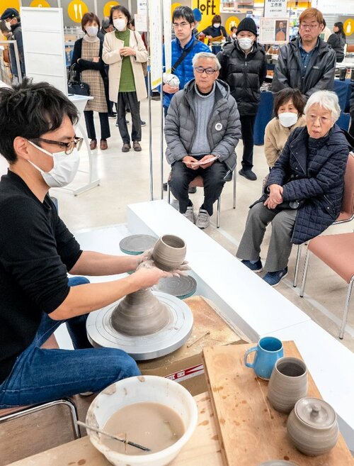 ろくろを回す窯元の実演に見入る来場者ら