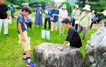 鳥取県立博物館前庭に展示されている佐治川石の特徴などを解説するこども学芸員の児童たち