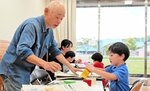 子どもたちに遊びを教える会員（左）＝１０月１９日、湯梨浜町はわい長瀬のハワイアロハホール