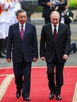 　２０日、ベトナム・ハノイでトー・ラム国家主席（左）と歓迎式典に参加するロシアのプーチン大統領（ロイター＝共同）