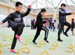 選手（右端）に教わりながらミニハードルを使ったトレーニングに挑戦する児童たち＝１５日、新温泉町湯の健康公園すこやかドーム