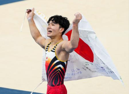 　体操男子個人総合で優勝し、日の丸を手に笑顔の岡慎之助＝パリ（共同）